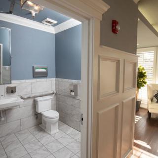 A modern bathroom with blue walls and tiled flooring, featuring a toilet and sink.