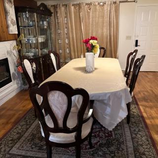 A dining room with a table set for six, featuring a vase of flowers as a centerpiece.