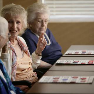 A group of elderly people engaged in conversation while playing bingo.