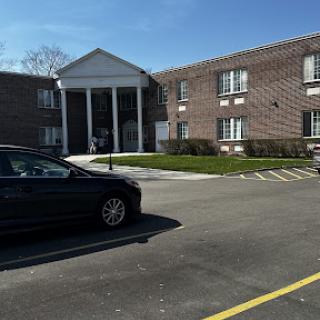 A view of a residential building with a parked car in a well-lit parking lot.