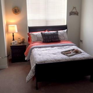 A cozy bedroom with a neatly made bed, soft lighting from a bedside lamp, and simple decor.