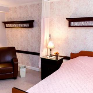 A cozy bedroom with a comfortable armchair, bedside lamp, and neatly made bed.