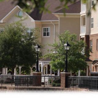 A scenic view of a residential building surrounded by trees and lamp posts.