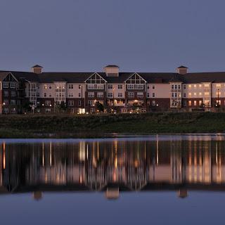 A serene lakeside hotel beautifully illuminated at dusk, reflecting on the water.