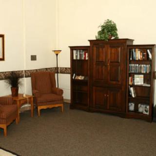 A cozy living room with a wooden bookshelf, armoire, and two armchairs.