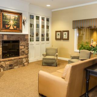 A cozy living room with a stone fireplace, armchairs, and a sofa under warm lighting.