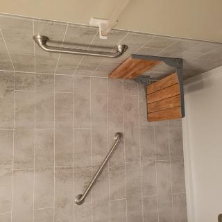 Accessible shower with grab bars and a folding seat.