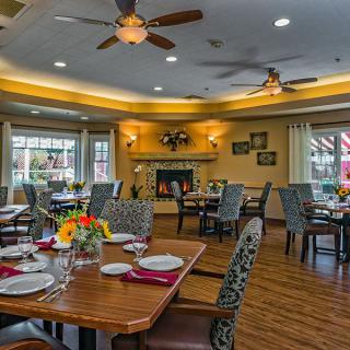 A cozy dining room with elegantly set tables and warm lighting.