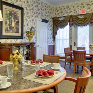 A cozy dining room with an elegant table setting and floral wallpaper.