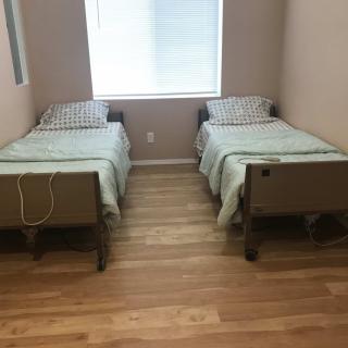 A minimalist bedroom with two twin beds and a window.