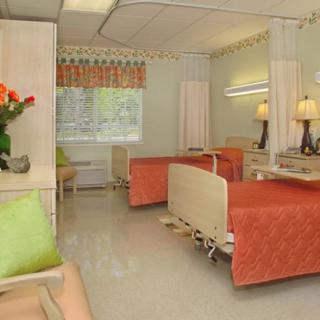 A well-furnished hospital room with two beds, curtains, and decorative flowers.