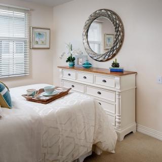 A cozy bedroom interior with a white dresser and decorative mirror.