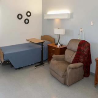 A hospital room with a bed, recliner chair, and bedside table.
