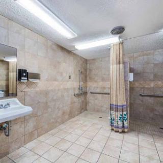 A spacious and clean bathroom featuring a shower area with tiles, a sink, and bright overhead lighting.
