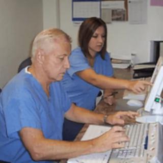 Medical professionals working together at a computer in an office setting.