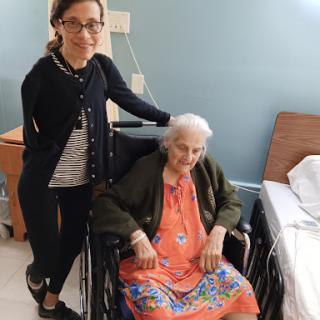 A touching moment between a caregiver and an elderly woman in a hospital setting.