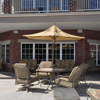 A cozy outdoor patio area with furniture and an umbrella in front of a brick building.