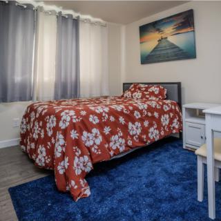 A cozy bedroom with a floral bedspread and blue rug.