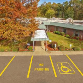 An aerial view of a building entrance with handicap parking spaces and autumn trees.