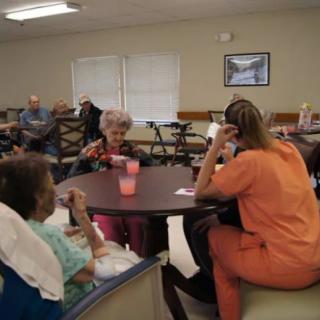 Caregivers and seniors gather in a nursing home common area.