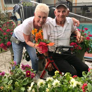 A happy pair surrounded by vibrant flowers in a garden setting.