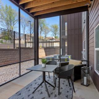 A cozy screened patio with a table, chairs, and potted plants.