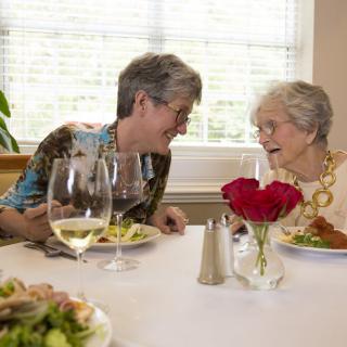 Two elderly women enjoying a meal and conversation together.