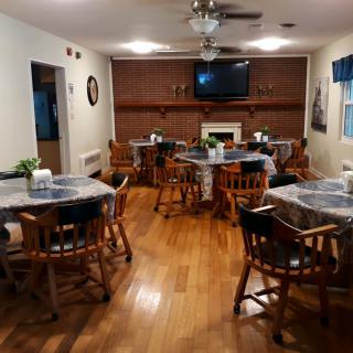 A cozy dining area with wooden tables and chairs, featuring a fireplace and a television.