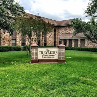 A well-maintained building with lush green grass and a prominent sign.