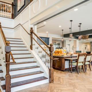 A modern open-floor plan featuring a staircase adjacent to a spacious kitchen with dining seating and pendant lighting.