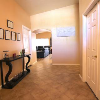 A well-lit hallway with stylish furniture and decor leading to another room.