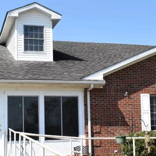 A brick house with a shingled roof and large windows.