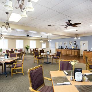 Spacious dining area with tables and chairs, featuring ceiling fans and ambient lighting.