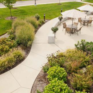 A beautifully landscaped garden with a patio area featuring outdoor furniture and lush greenery.