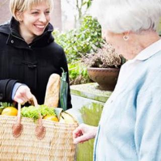 A person delivering groceries to an elderly individual, showcasing community support and care.