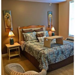 A cozy bedroom with a decorated bed, bedside tables, and artwork on the walls.