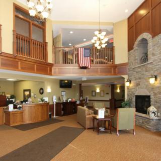 A spacious lobby with a reception desk, seating area, chandeliers, and a fireplace.