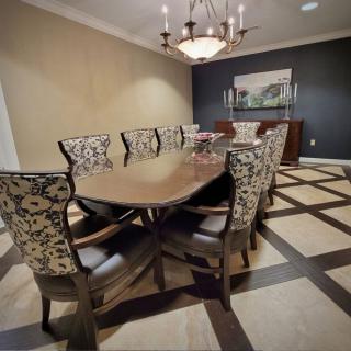 A sophisticated dining room featuring a large wooden table and patterned chairs, illuminated by an elegant chandelier.