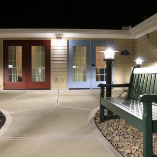 A well-lit outdoor area with a bench and colorful doors at night.