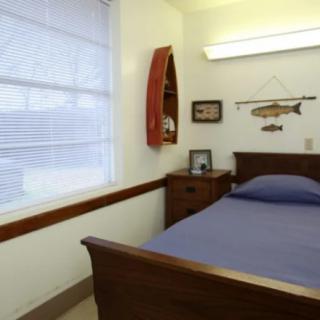 A simple bedroom with a single bed and fishing-themed decor.