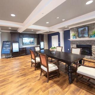 A modern dining room with a large table, surrounded by chairs, featuring hardwood flooring and a fireplace.