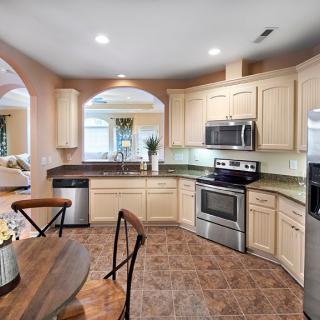 A modern kitchen with stainless steel appliances, wood cabinetry, and a small dining area.