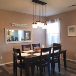 A cozy dining room with a dark wooden table, matching chairs, and a stylish light fixture.