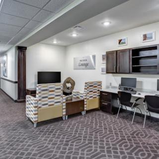 A modern lounge area featuring comfortable seating and designated workstations.