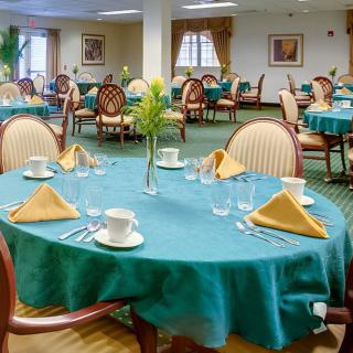 A well-arranged dining area with teal tablecloths, neatly folded napkins, and elegant chairs.