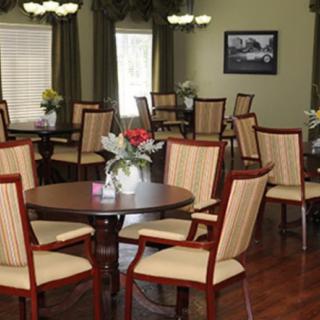 An elegant dining area with multiple wooden tables and striped chairs, decorated with flowers.