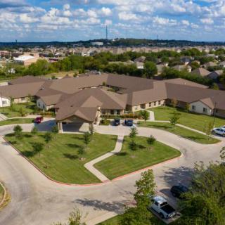 Aerial view of a suburban building with surrounding roads and parked cars.
