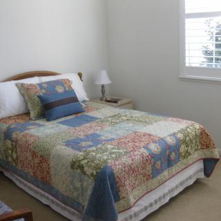 A cozy bedroom with a colorful quilt on the bed and a lamp on the side table.
