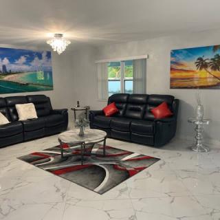 A modern living room with black leather sofas, contemporary artwork, and a stylish coffee table on a patterned carpet.