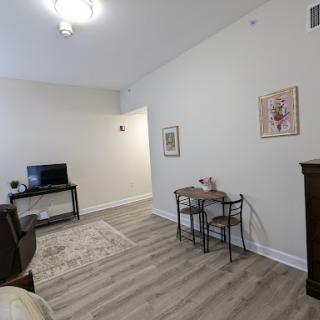 A cozy living room featuring a television, a small table, and decorative artwork.